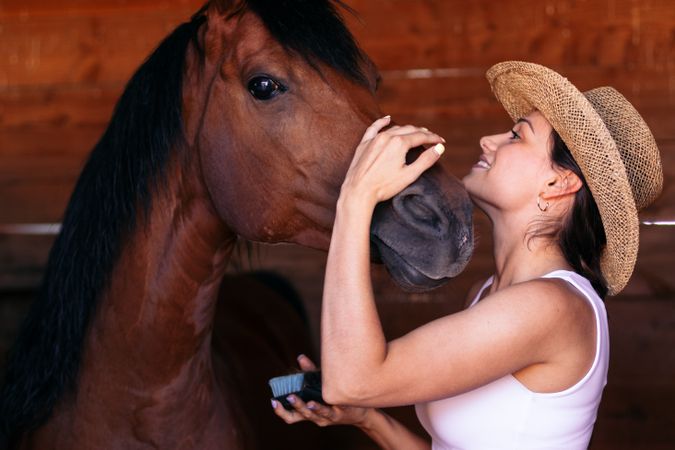 Woman taking care of his brown horse in an equestrian center