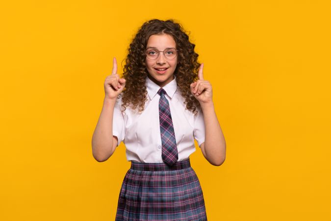 Girl wearing glasses pointing upwards with both hands