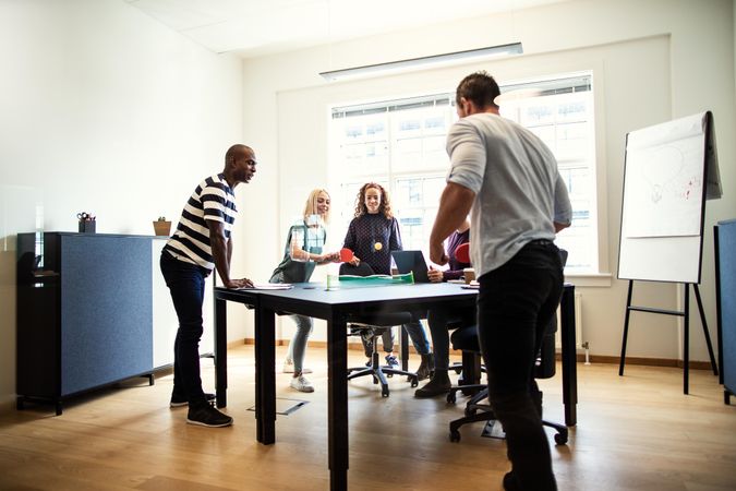 Group of people with miniature ping pong set in office