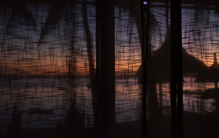 Tropical sunset behind hotel curtains