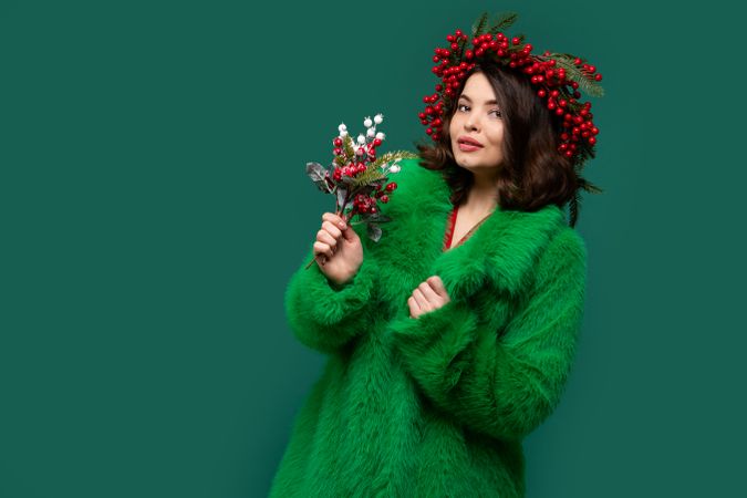 Smiling woman in green coat and red berry wreath