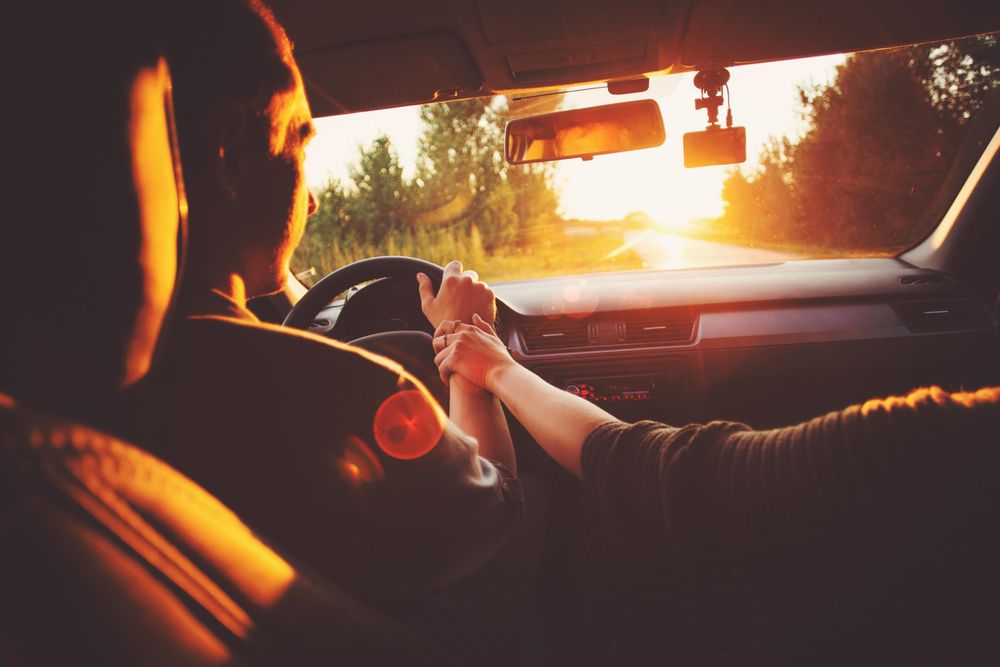 Inside of vehicle with man driving and passenger holding his hand