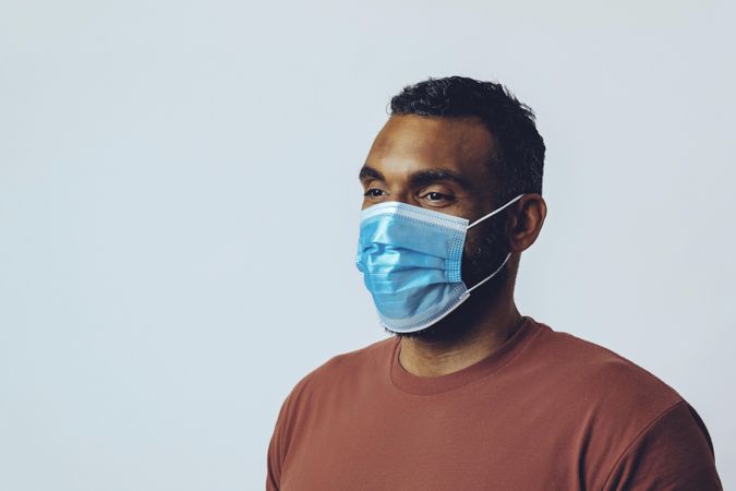 Male looking away from camera wearing medical face mask in studio shoot, copy space