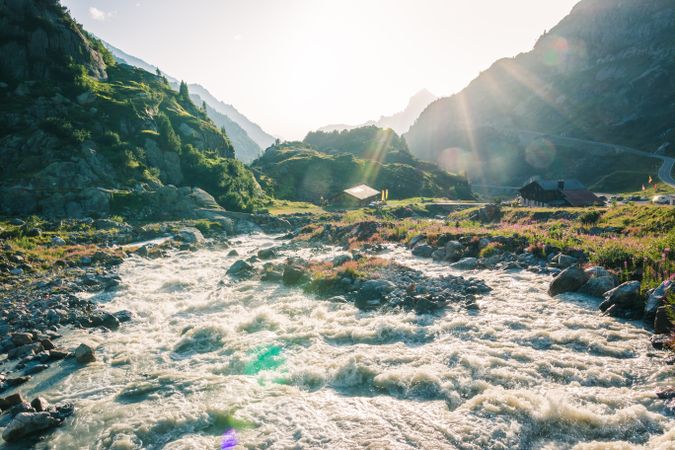 Foamy mountain stream flowing through stones in sunlight