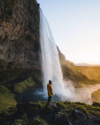 Person standing on rock near waterfalls during daytime