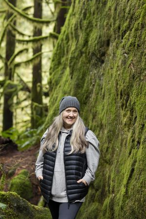 Smiling woman posed next to a mossy rock wall