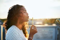 Woman on sunny day blowing bubbles outside