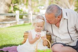 Grandfather and Granddaughter Enjoying Easter Eggs on Blanket At Park