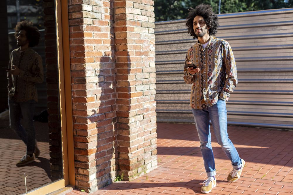 Man using a mobile phone while standing outdoors on a sunny day