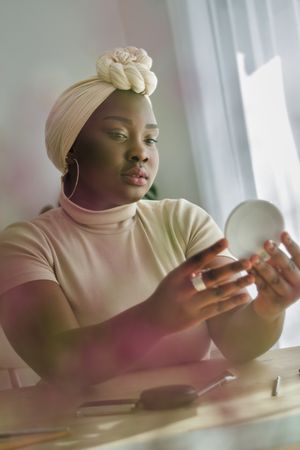 Charming Black woman admiring herself in front of mirror