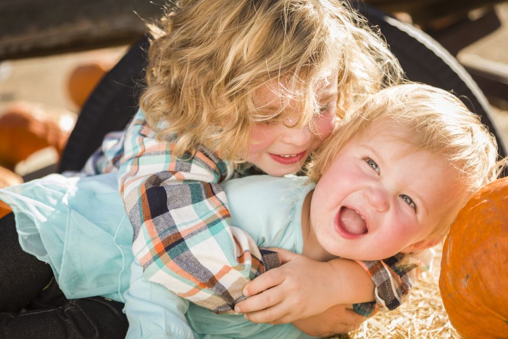 Little Boy Playing with His Baby Sister at Pumpkin Patch