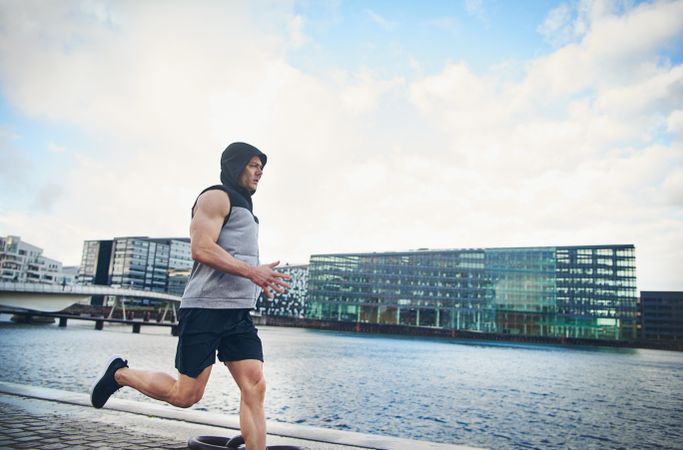 Muscular male in grey vest running outside on chilly day