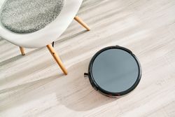 Robotic vacuum cleaner placed near chair on floor