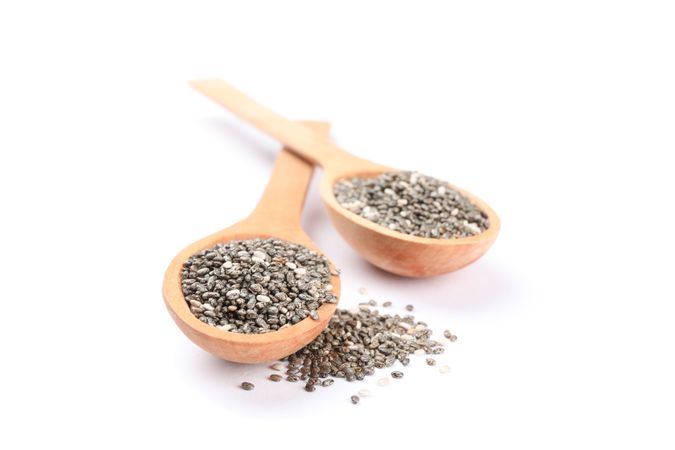 Chia seeds and wooden spoons isolated on blank background
