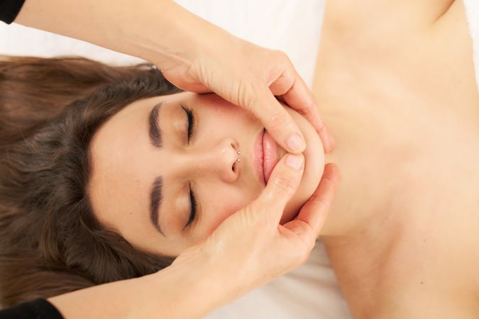 therapist massaging a woman's face. Attractive woman receiving facial