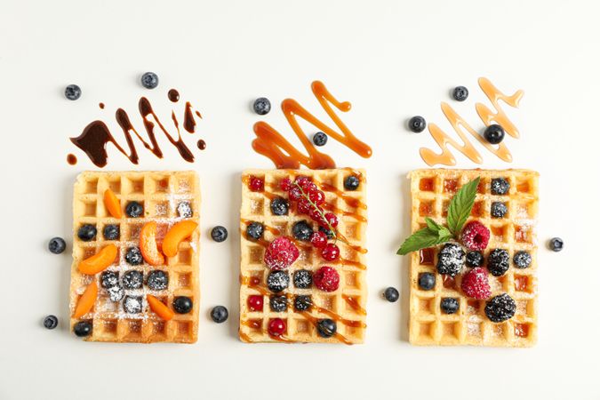 Flat lay composition with waffles and different toppings, top view