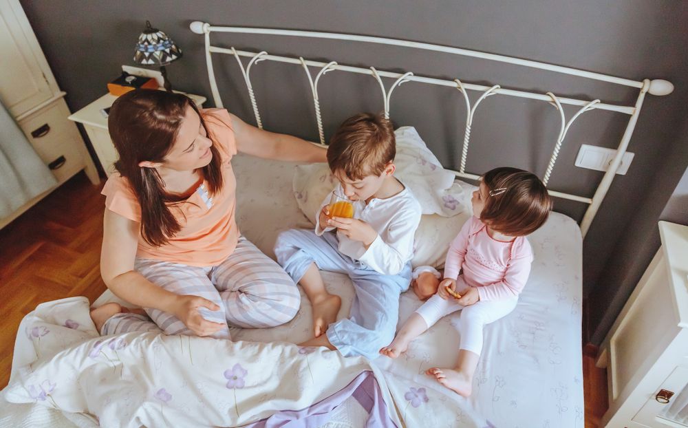 Top view of happy children having breakfast in bed with their mother on a relaxed morning
