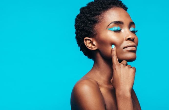Close up of young female model with vibrant makeup against blue background