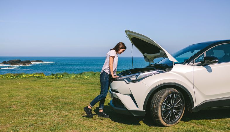 Woman looking engine of broken down car