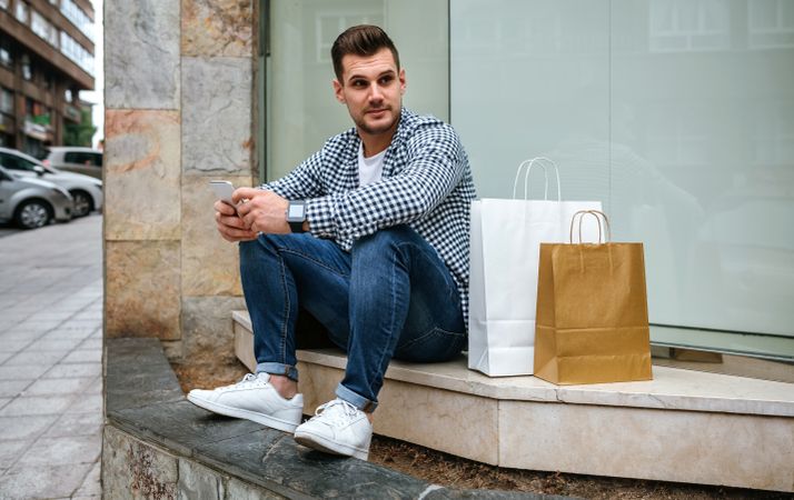 Young man with shopping bags sitting