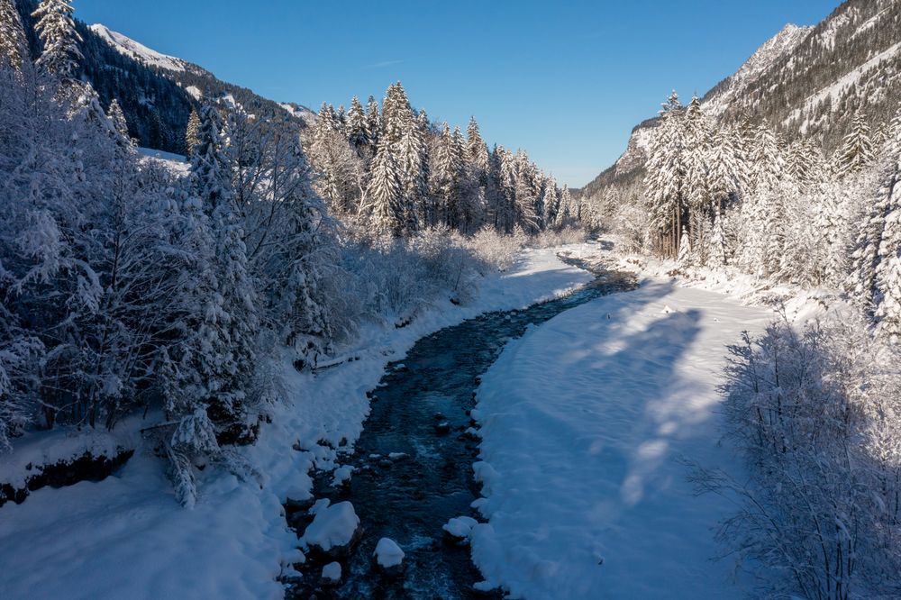 River in winter deep snow scenery, drone aerial view in the Bavarian Alps, Germany