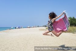 Woman jumping with beach wrap 0Ld1Zy
