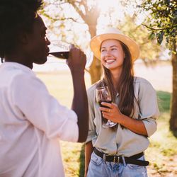 Man and woman smiling drinking red wine on a sunny day outdoors