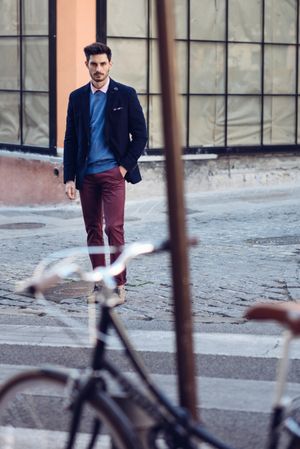 Attractive man in the street wearing elegant suit with vintage bicycle in foreground
