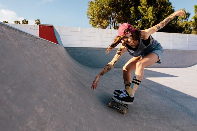 Skater female rides on skateboard at skate park ramp