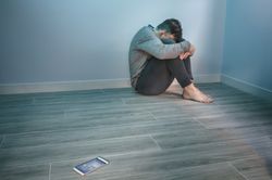 Man with problems sitting on the floor with mobile on the floor