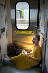 Cheerful female traveler in stylish dress at train