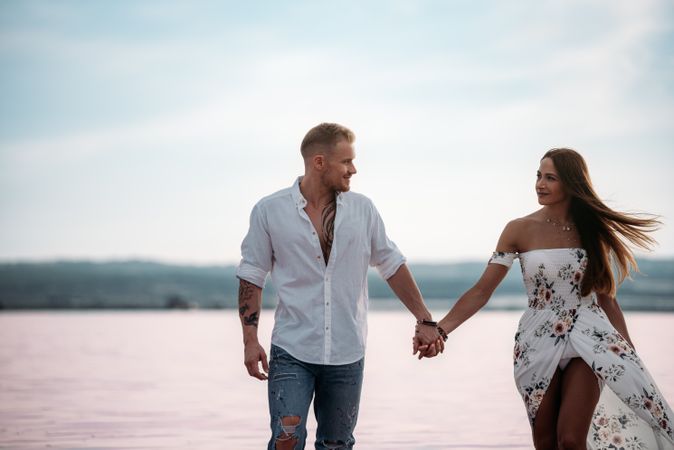 adorable couple walking into an amazing beach with pink water