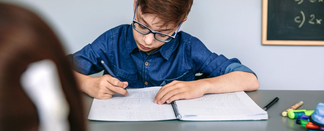 Teenager writing in notebook at school