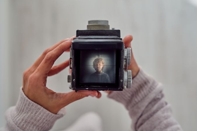 Crop photographer with photo of boy on retro camera display
