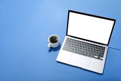 Looking down at blue room with laptop with mock up screen with cup of coffee with copy space