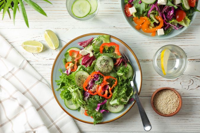 Fresh salads with spices on rustic wooden background, top view
