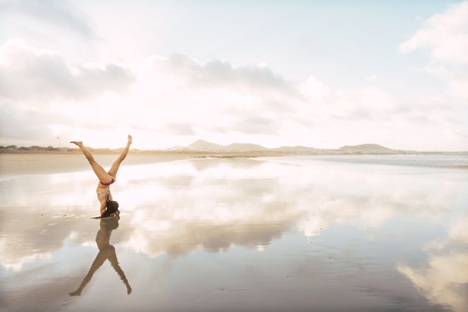 Woman doing handstand near sea