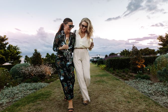 Sophisticated women walking outdoors with wine