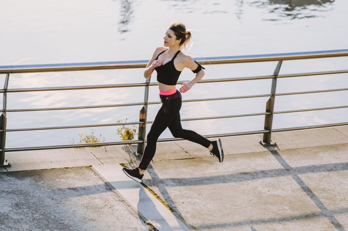 Woman running on embankment near water