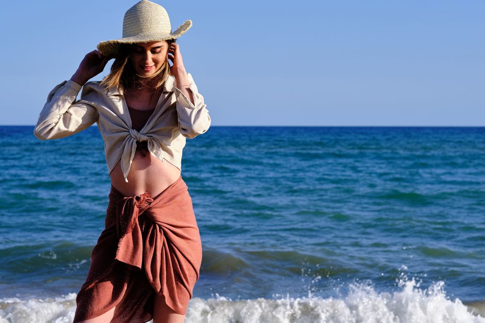A fashion model with a hat at the beach before sunset