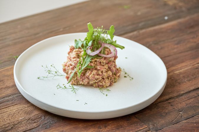 Delicious tartar with greenery on wooden table