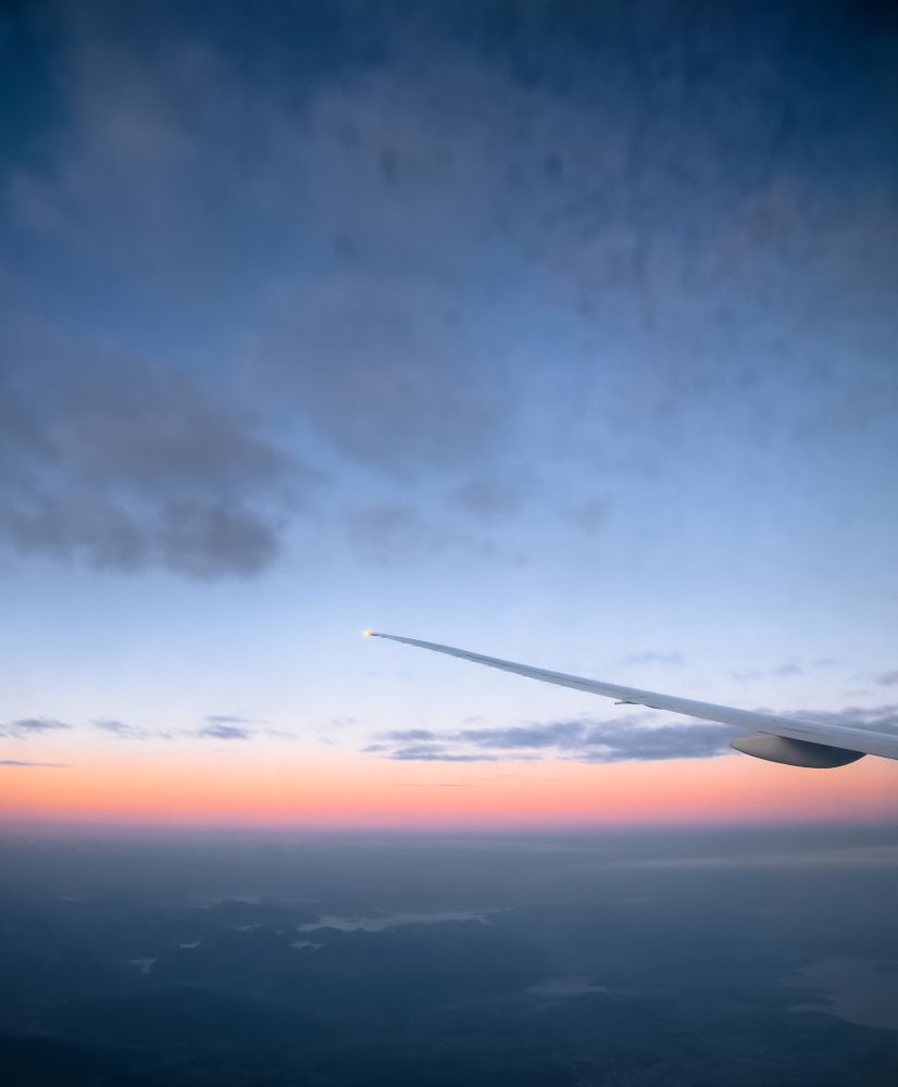 Airplane wing under blue sky during sunset