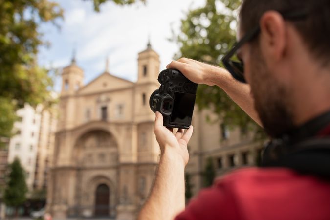A young man, a traveler, taking pictures with a digital camera of a monument in Spain