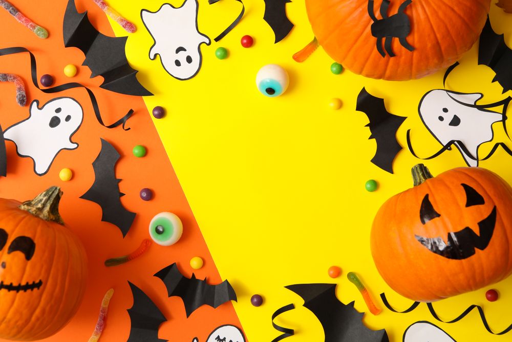 Different halloween accessories and pumpkins on two tone background