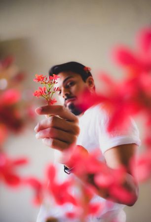 Man in light shirt holding red flower