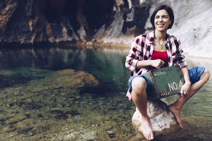 Woman with picnic case on rock in water