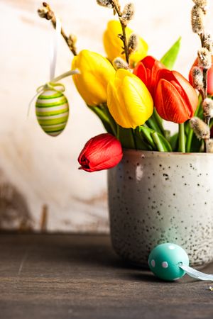 Easter card concept with egg decorations around vase of tulip