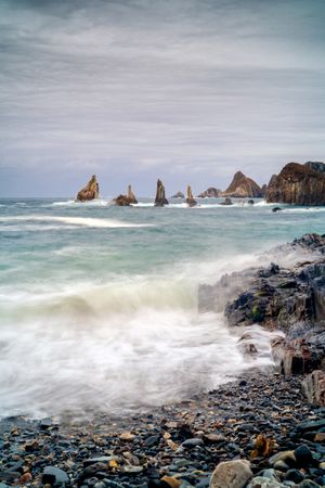Rocky peaks protrude from water in cloudy day