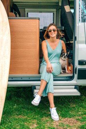 Happy woman relaxing on stoop of motorhome door with cute dog