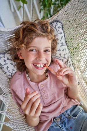 Cheerful boy finishing eating ice cream in hammock